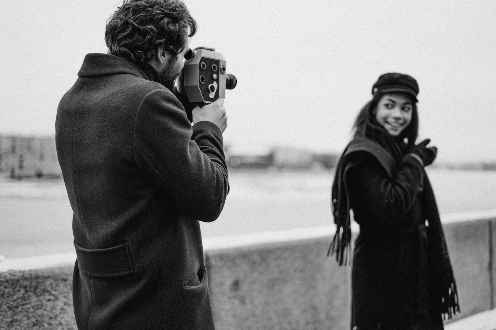 Black-and-white street scene with a filmmaker using a vintage camera